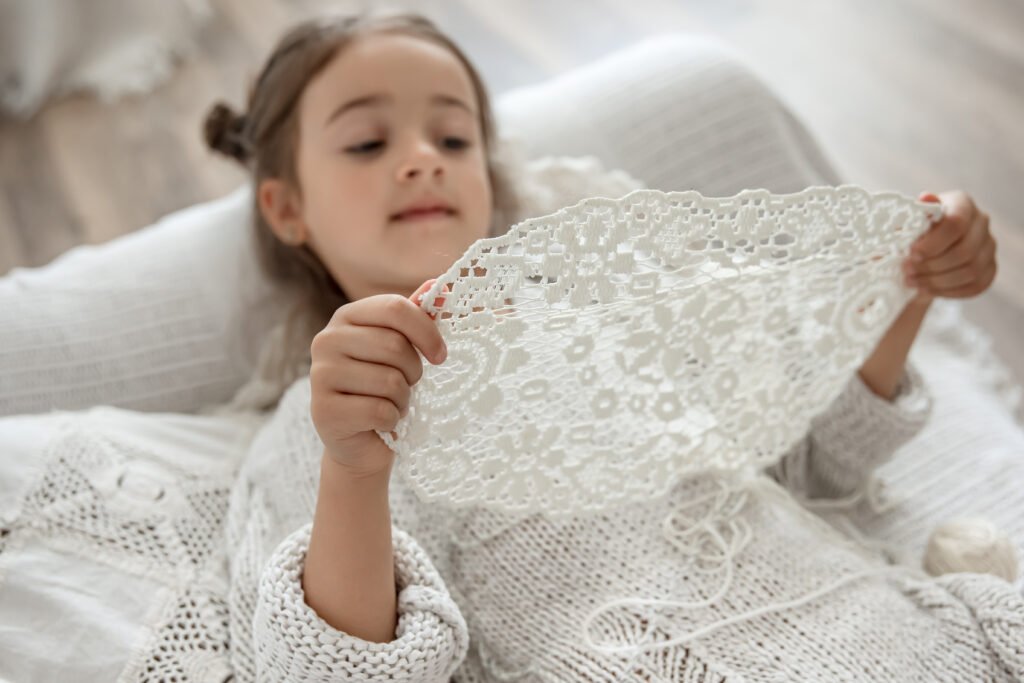 enfant cute little girl holding a handmade openwork napkin in her hands.
